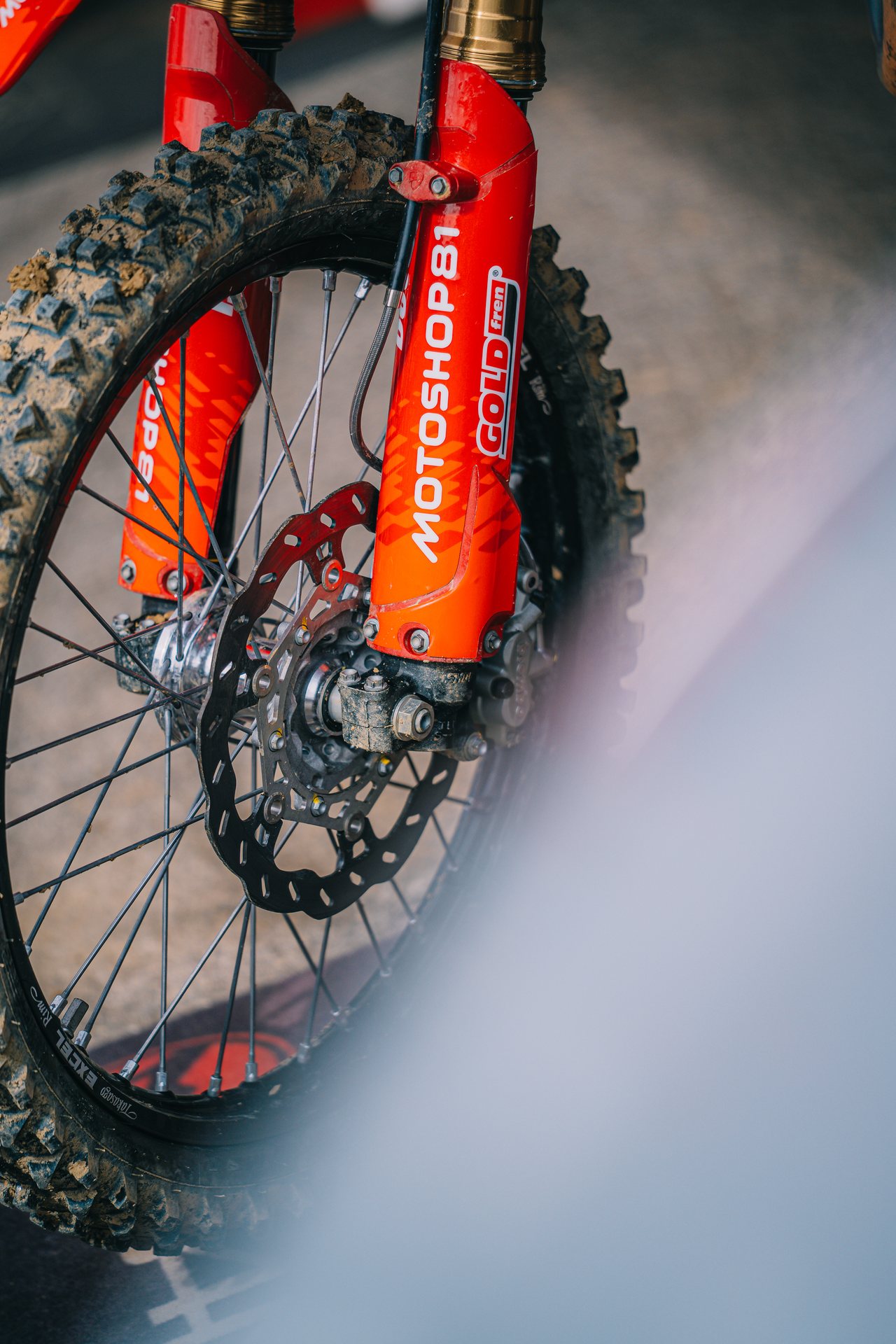 Predný brzdový kotúč, koleso a vidlica motocrossovej motorky s polepom MOTOSHOP81.