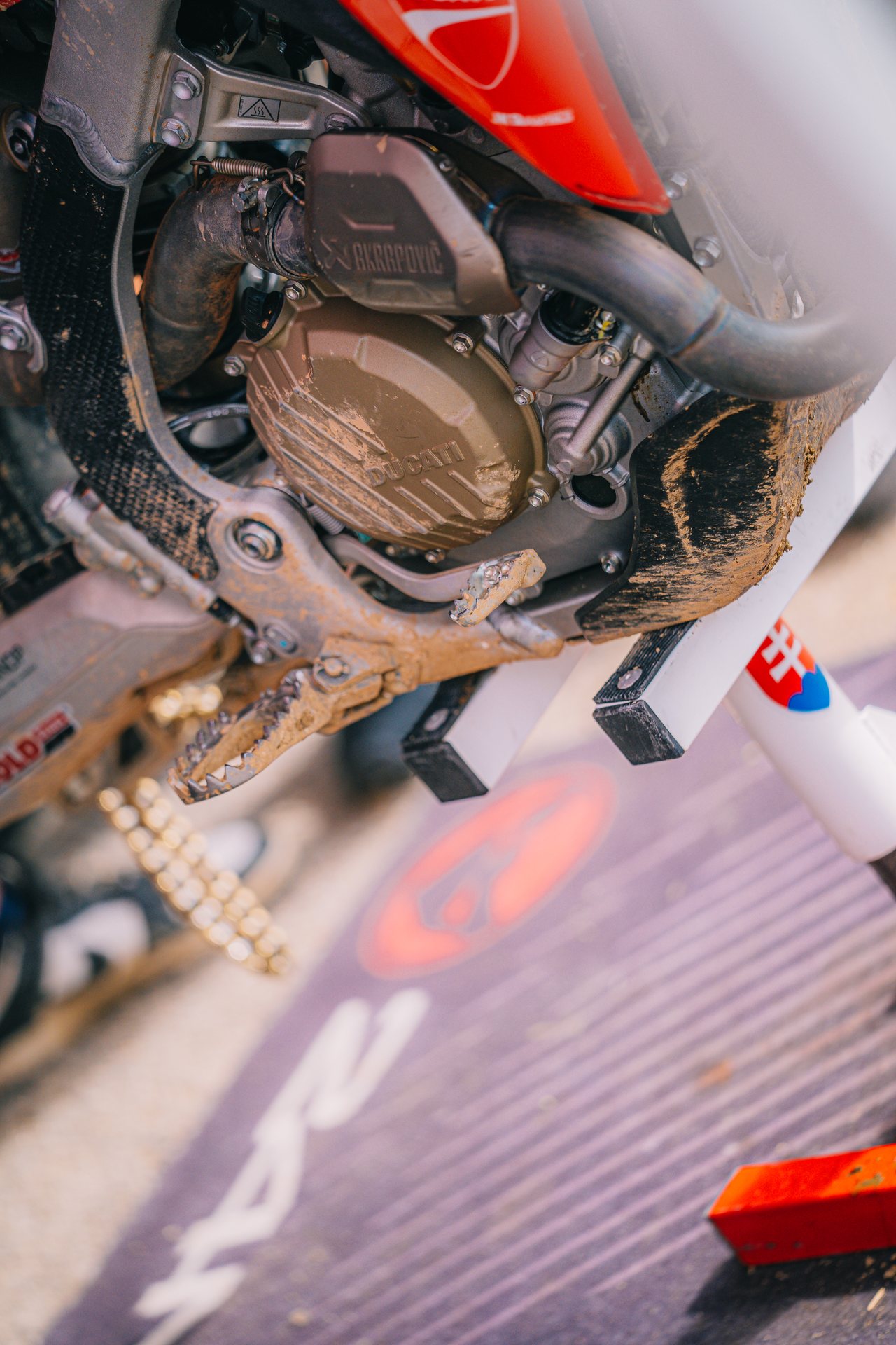 Zablatený motor, kryt a stúpačka motocrossovej motorky po jazde.